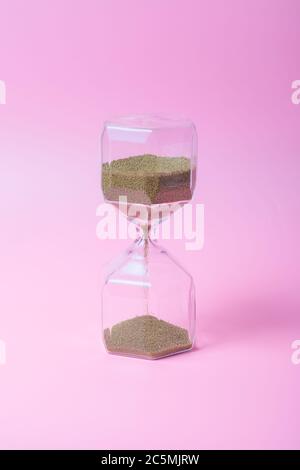 Hourglass with transparent glass on pink background Stock Photo