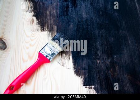 Natural wooden pine board painted in dark color. Paint brush on a painted board. Beautiful wood background Stock Photo
