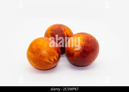 Three Sicilian ​​oranges on a white plate on a white background.  Sicilian oranges against background. Healthy and tasty red ​​orange. Stock Photo