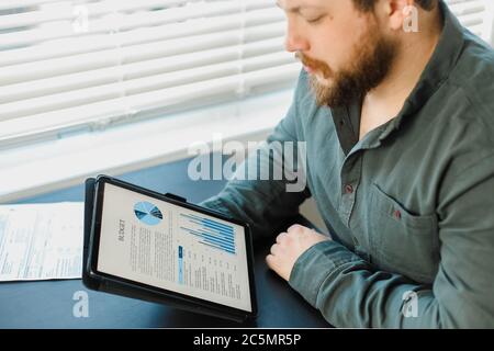 Economist working with graphs and diagrams on tablet at office. Stock Photo