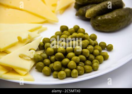 Beautiful green peas, cucumbers and sliced cheese on white plate  against background. Keto diet with very healthy and tasty meal for lunch Stock Photo
