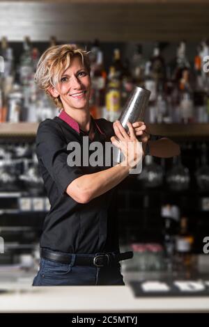 Bartender woman looking at camera preparing a drink. Stock Photo