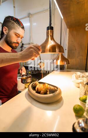 Chef finishing a plate inside gourmet restaurant kitchen. Stock Photo