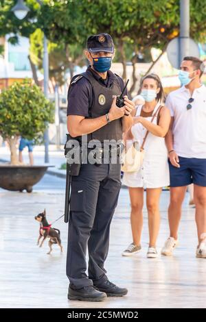 Punta Umbria, Huelva, Spain - June 3, 2020: Spanish police  with 'Local Police' logo emblem on uniform maintain public order in the street Calle Ancha Stock Photo