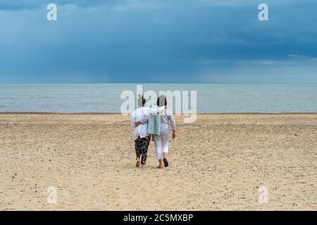 Southwold Suffolk England. Mother and daughter walking on the beach. 1 July 2020 Model released photograph of Mother and Daughter walking to the sea s Stock Photo