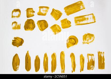 Gold color brush strokes against white background. Golden Abstract brush marks.Handmade design elements for use.Painted grunge stripes set  for  backg Stock Photo