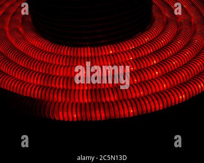Red corrugated hose glowing from the inside in the dark Stock Photo