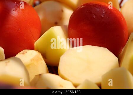 Chopped fresh potato pieces with red tomato together display ready to cook. Stock Photo
