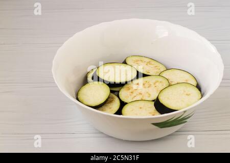 Eggplant, sliced with slices, are in bowl on a white background, Closeup Stock Photo