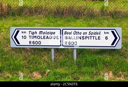 Destination road signs to Timoleague and Ballinspittle in Gaelic and English languages, County Cork, Republic of Ireland.  Eire. Stock Photo