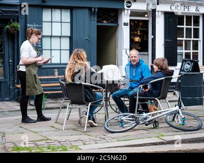 Rochester, Kent UK. 4th July, 2020. A waitress serves customers at a restaurant, Smoke and Liquor, in Rochester High Street. The U.K reopens pubs, restaurants, barbers, hairdressers and hotels on July 4th after being closed since March due to the Coronavirus Outbreak. Credit: Yousef Al Nasser/ Alamy Live News Stock Photo