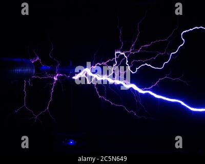 Bright white-blue electric lightning emanates from electric coils in the dark Stock Photo