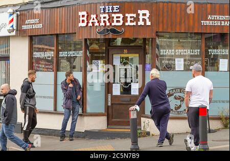 Kidderminster, UK. 4th July, 2020. After months of forced closure during the coronavirus lockdown, hairdressers and barbers in England can now reopen for business. Men patiently queue in the street, desperate for the services provided by this authentic Turkish barber shop. Whether attending to hair growth on the head or the chin, these men are quite prepared to accept the 'new normal' and queue for a much-needed, overdue trim. Credit: Lee Hudson/Alamy Live News Stock Photo