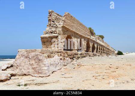 The ruins of the ancient Roman Aqueduct in city of Caesarea Maritima are located by the sea shore of Israel Stock Photo