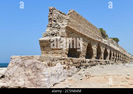 The ruins of the ancient Roman Aqueduct in city of Caesarea Maritima are located by the sea shore of Israel Stock Photo