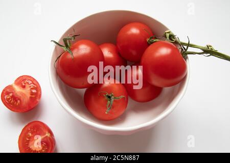 Fresh cherry tomatoes in a white bowl on white background Stock Photo