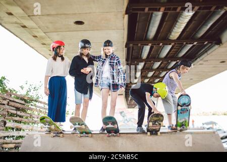 Group of friends children at skate ramp. Portrait of confident early teenage friends hanging out at outdoor city skate park. Little skateboarders Stock Photo