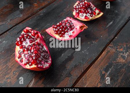 Organic cut of pomegranate over old dark wooden table, side view. Stock Photo