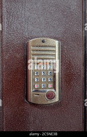an intercom with a microphone and speaker for ringing an apartment with a keypad for dialing and a scanner key chip for access on iron doors, close up Stock Photo