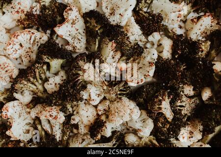Roasted broccoli and cauliflower on a white baking tray with spices and oil Stock Photo