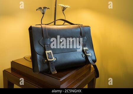Handmade black leather bag on the background of an expensive lamp.  Stock Photo