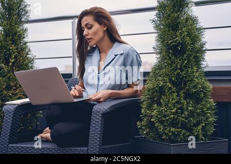 Beautiful young woman using laptop on rooftop terrace Stock Photo