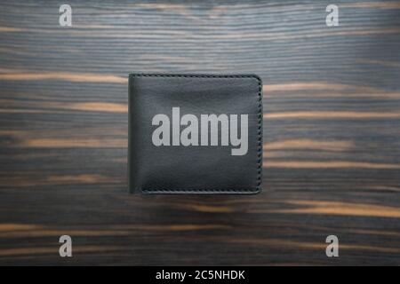 Black handmade leather wallet on a dark wooden background. Top view Stock Photo