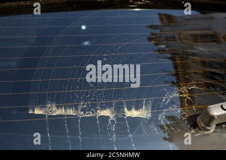 glass of a dirty car in stains of dirt and dust after cleaning by a car wiper close-up of the rear window. Stock Photo