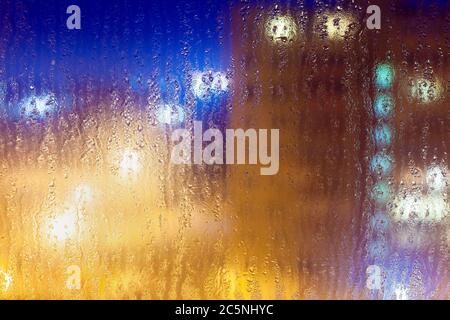Abstract background with light colorful multi-colored highlights on a wet glass in rainy night weather. Stock Photo