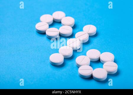 Symbol of the percentage of diseases and recovered patients laid out of white tablets on a blue background. Stock Photo