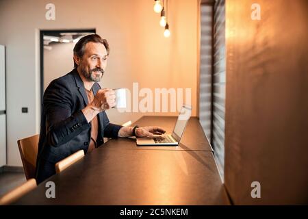 Businessman sitting at office desk having a coffee break Stock Photo