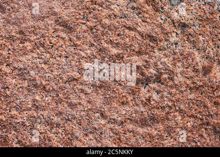 Background granite is a red stone with small black and white spots on the entire surface. Texture for an inscription, text, or logo. Stock Photo
