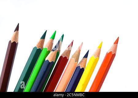 Nine different colored wood pencil crayons scattered on a white paper background Stock Photo