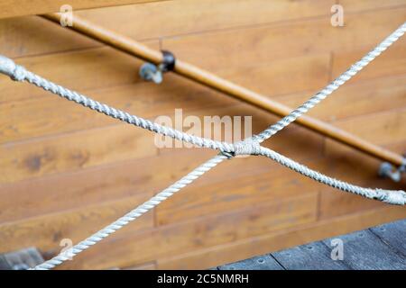 Decorative rope knotted, against a background in bokeh wooden boards with a handrail on the descent. Stock Photo