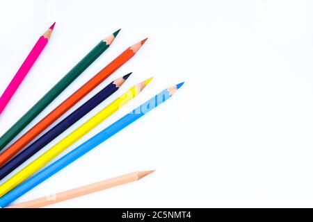 Six different colored wood pencil crayons scattered on a white paper background Stock Photo
