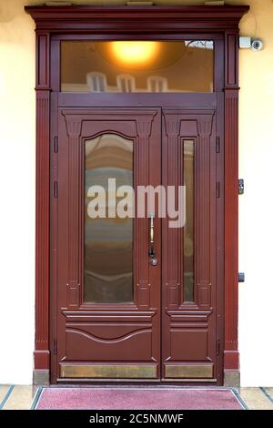 Brown entrance double door with glass inserts and a window above the door in retro style outside the building. Stock Photo