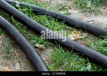 pvc corrugated pipe black colore lying on the ground with green grass. Stock Photo