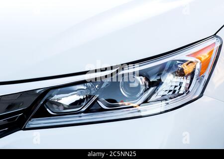 car headlight close up, xenon light with lens on a white car. Stock Photo