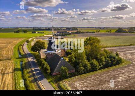 Aerial view of small dutch hamlet with historic wooden windmill in agricultural countryside landscape, Groningen, Netherlands.
