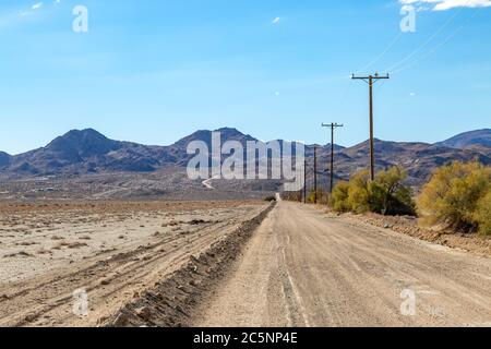 An unpaved road in the Californian desert, with rugged hills in the distance Stock Photo