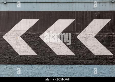 Painted arrows pointing the way, on the wall of an urban building Stock Photo