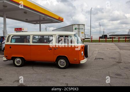 A vintage orange Volkswagen Bus T2b Transporter drives away after refueling at a Lake Placid, Florida Shell gas station. Stock Photo