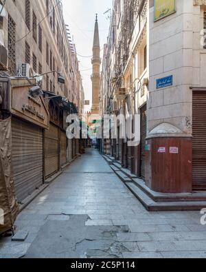 Cairo, Egypt- June 26 2020: Alley in old historic Mamluk era Khan al-Khalili famous bazaar and souq, with closed shops, and minaret of Al-Hussein Mosque in the far end, during Covid-19 lockdown Stock Photo