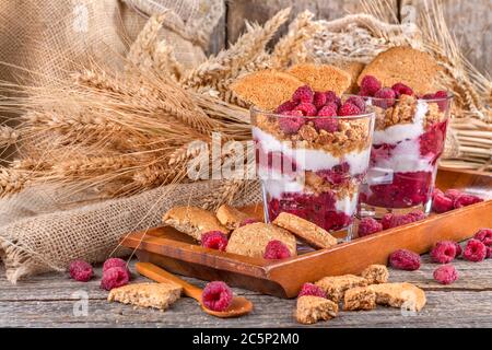 A healthy meal with fresh raspberries, cream, and biscuits of rye. Vintage style composition on a rustic wooden table. The concept of healthy eating. Stock Photo
