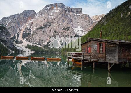 high angle view of iconic boathouse and boats with mount Seekofel mirroring in the clear calm water of  Pragser Wildsee (Lago di Braies) in Dolomites, Stock Photo