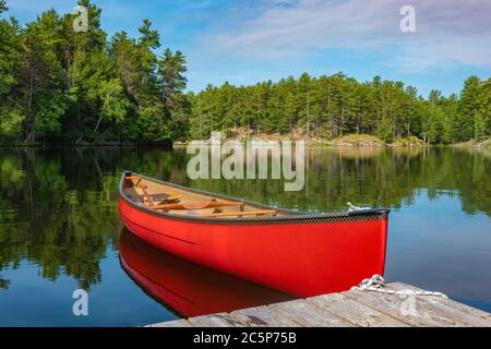 Canoe tied to a dock on the calm waters of Stony Lake when it is calm and serene, Stock Photo