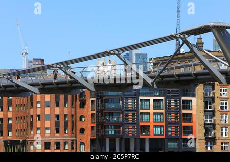 The Millennium Bridge over the River Thames with modern riverside offices and apartments beyond, UK Stock Photo