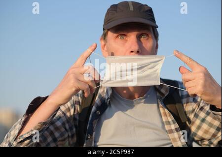 Caucasian man in casual clothing holds a medical mask outdoors Stock Photo