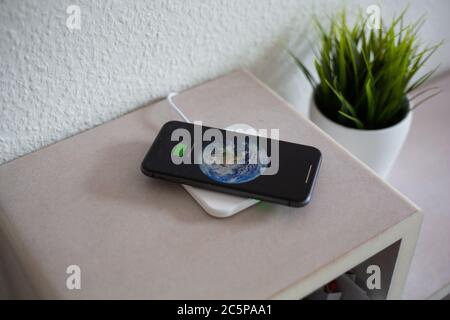 Smartphone on wireless charging pad to charge battery Stock Photo