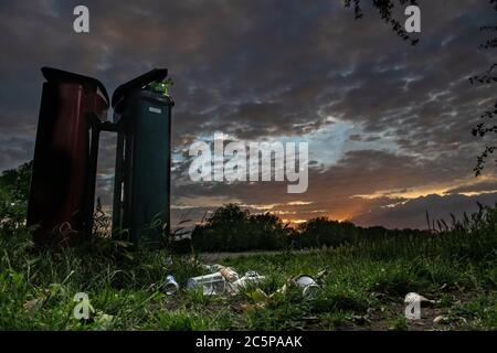 Overflowing bins in a London park at the end of the day under a dramatic sunset Stock Photo